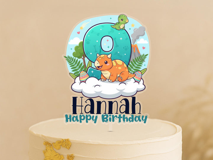 A birthday cake topper with a dinosaur and clouds, along with the text &quot;Hannah Happy Birthday&quot;.