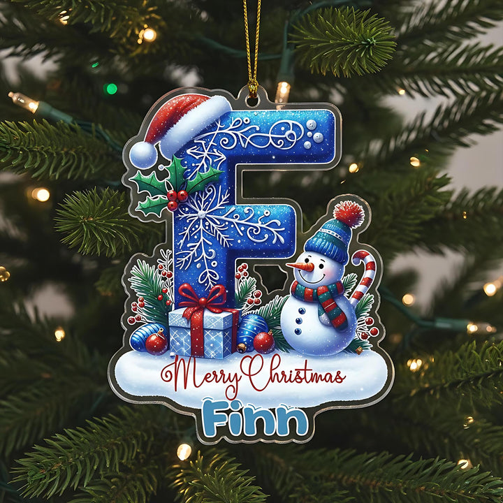 A Christmas ornament with a snowman, presents, and a letter &quot;F&quot; on a tree.